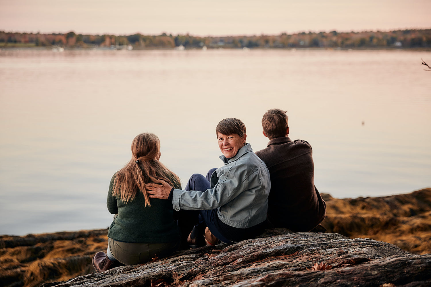 Marjie Longshore looking back while sitting with her kids at a scenic Maine location near water