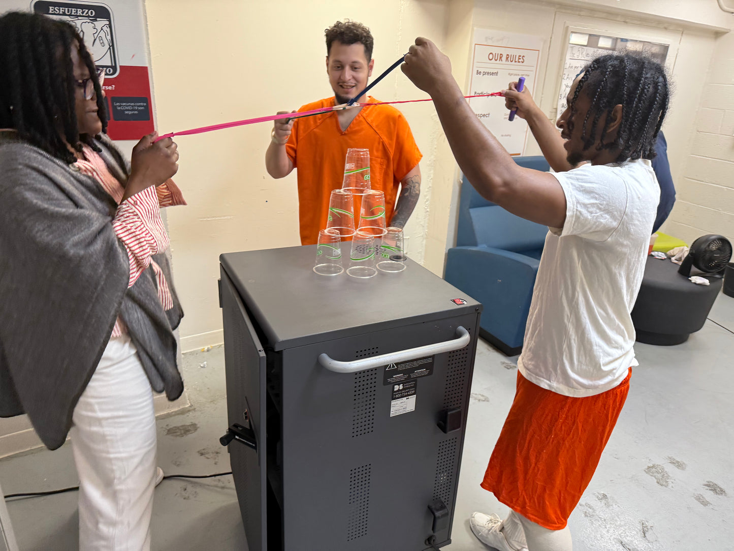 Three people playing cooperative cup stacking game inside.